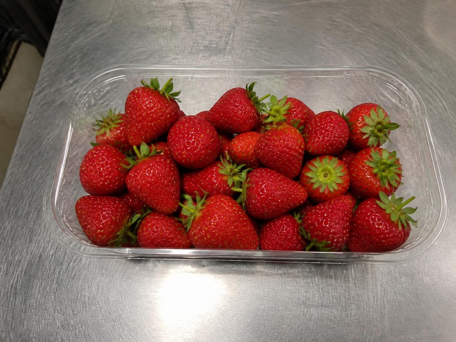 Tray of bright red ripe strawberries with green stems, no visible defects